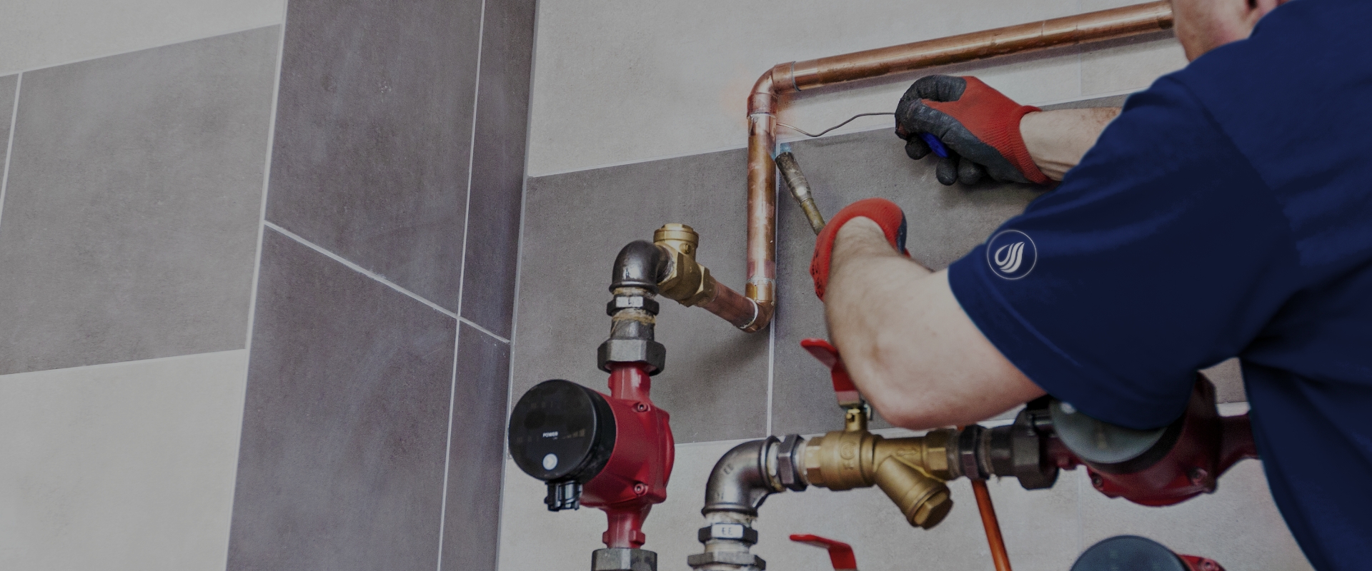 Plumber fitting copper lines and brass valves at a wall-mounted pump