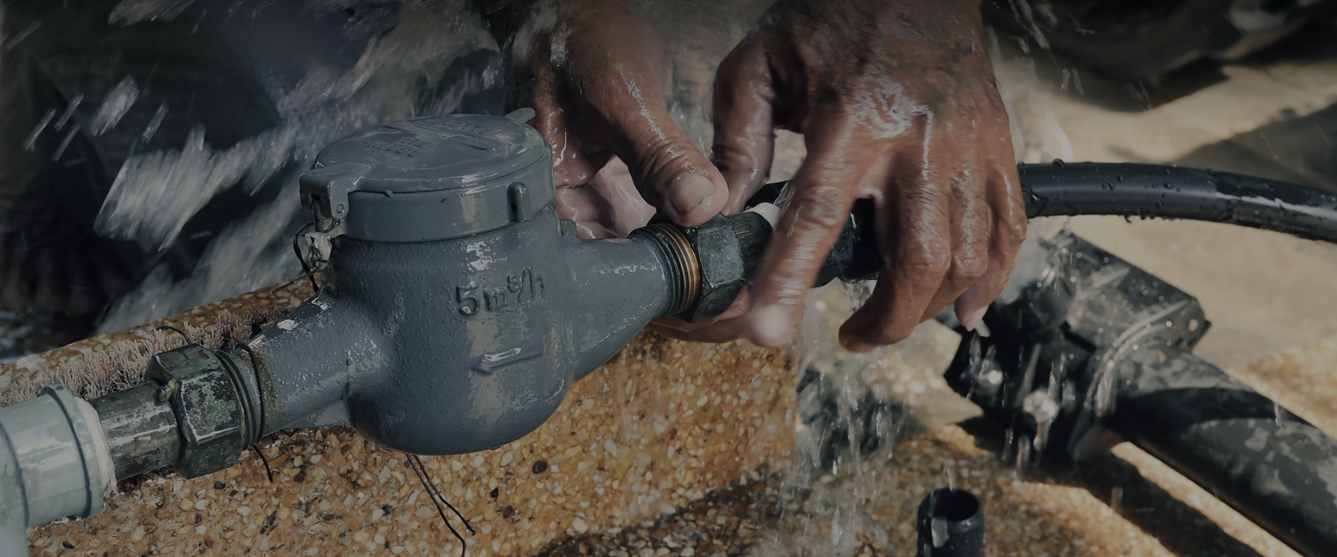 Hands working on a water meter and service line connection